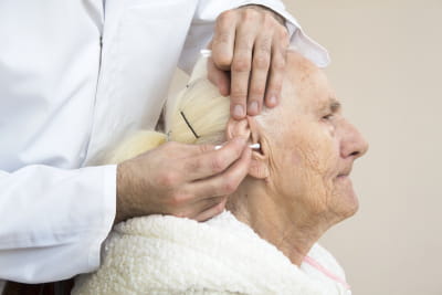 caregiver cleaning the ear of senior woman